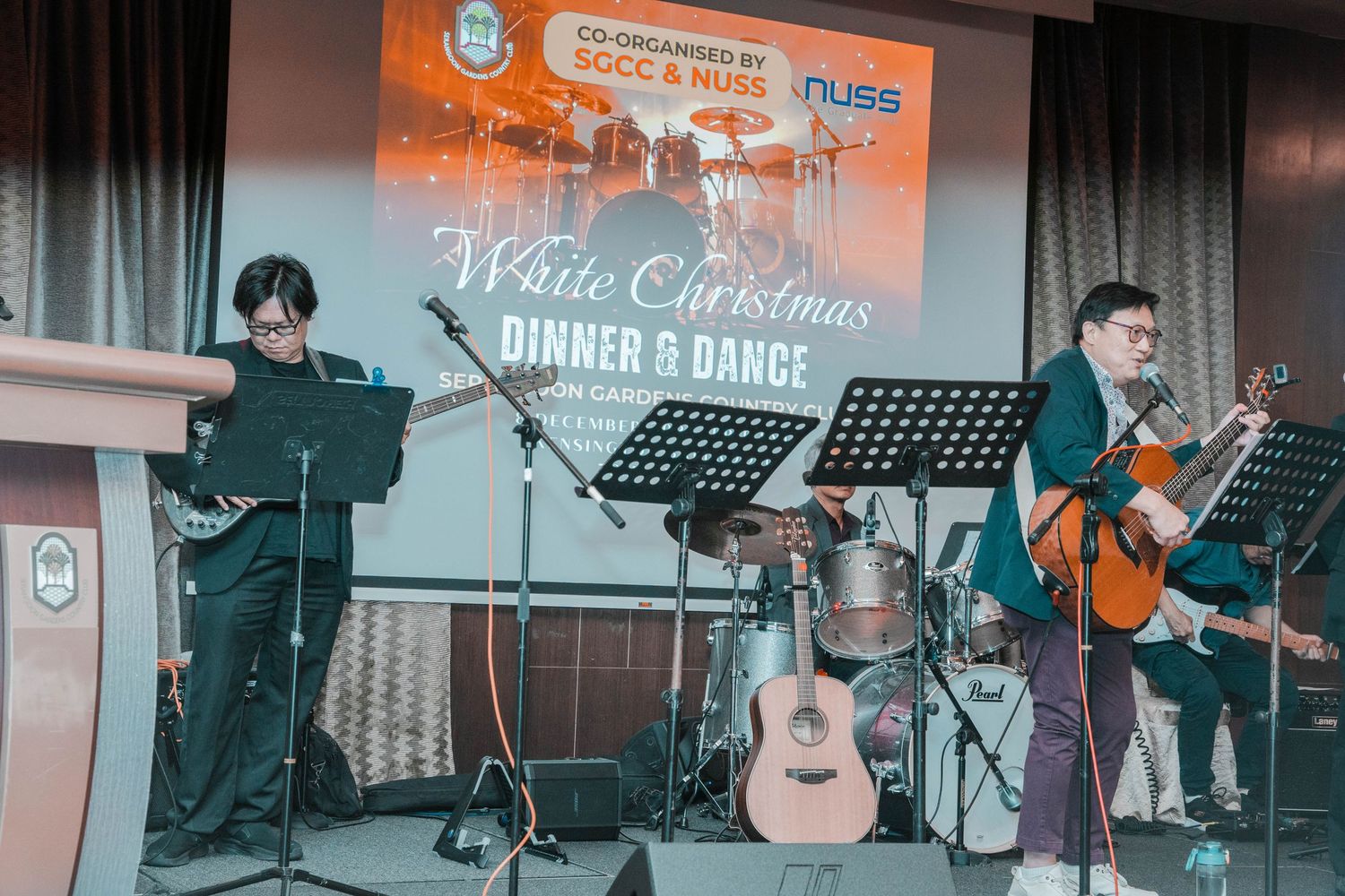 Musicians performing at White Christmas concert with acoustic instruments and microphone setup.