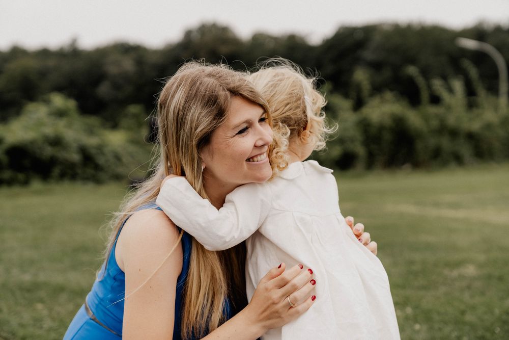 Heartwarming embrace shared on grassy field during sunny day.