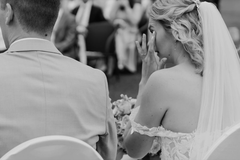 Emotional ceremony moment captured in black and white with veil detail.