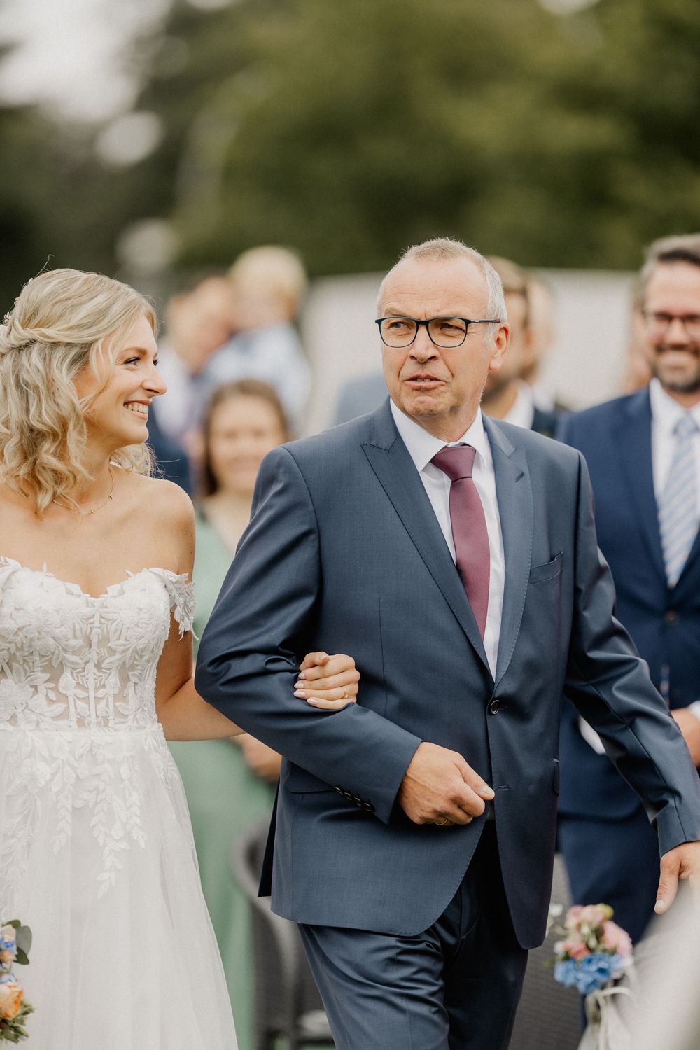 Outdoor wedding ceremony with duo walking down path in formal attire.