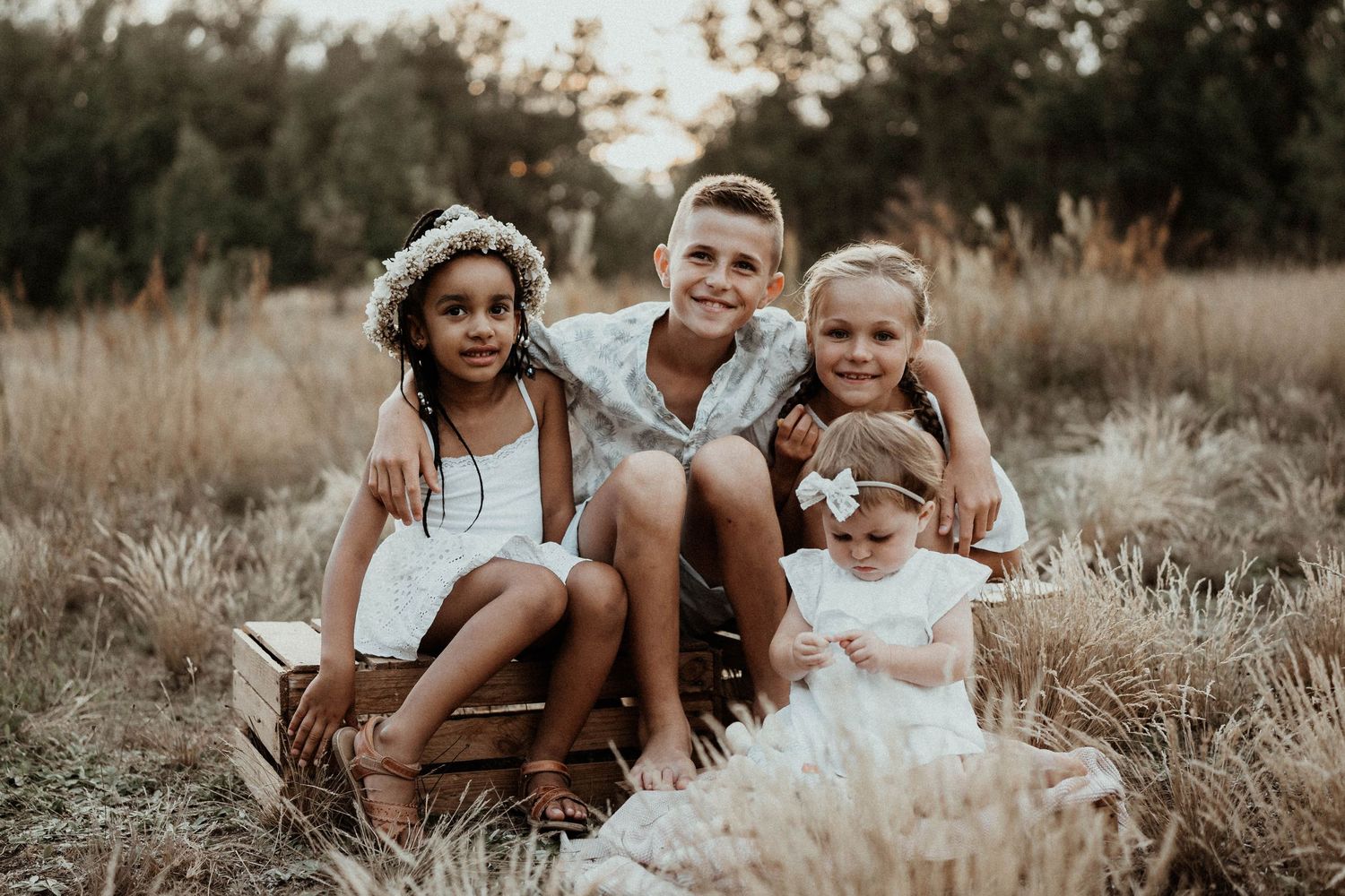 Group sitting together in a field of tall grass during golden hour.