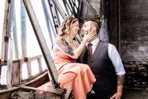 A romantic couple in vintage attire share an intimate moment while sitting on industrial stairs.