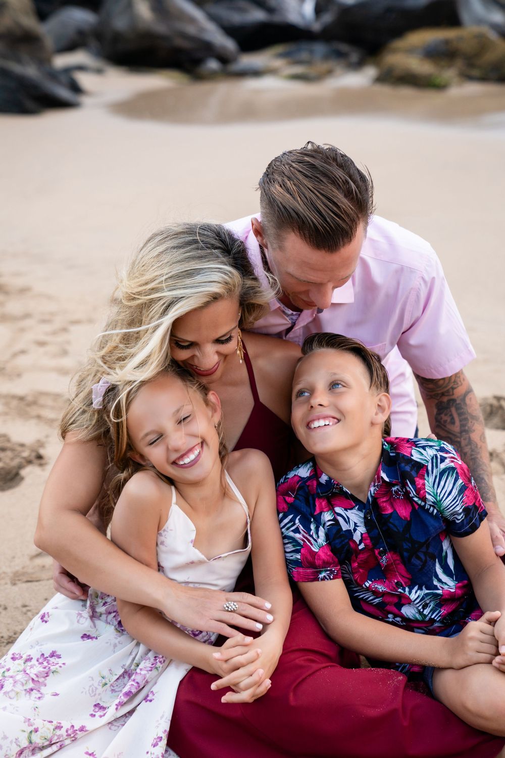A joyful family moment captured on a tropical beach with volcanic rocks in the backdrop.