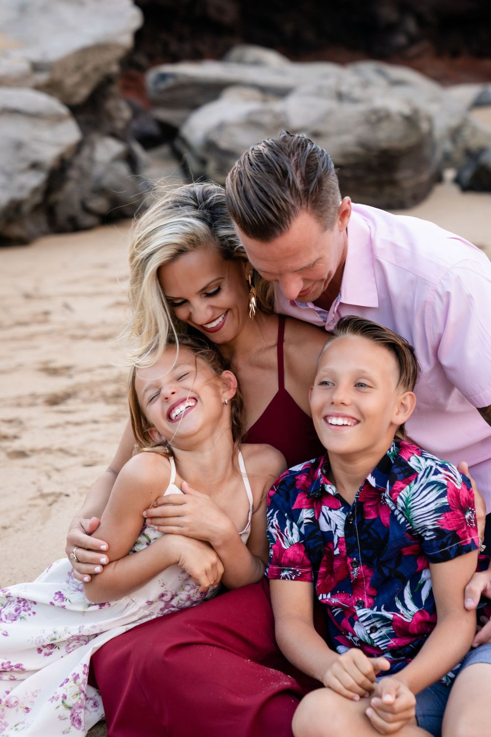 Family shares laughter and embraces while relaxing on a beautiful Hawaiian beach.