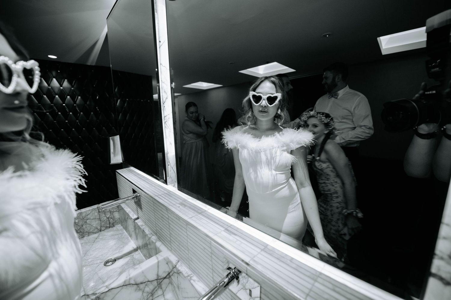 Black and white photo of bride wearing sunglasses and white dress in retro style.
