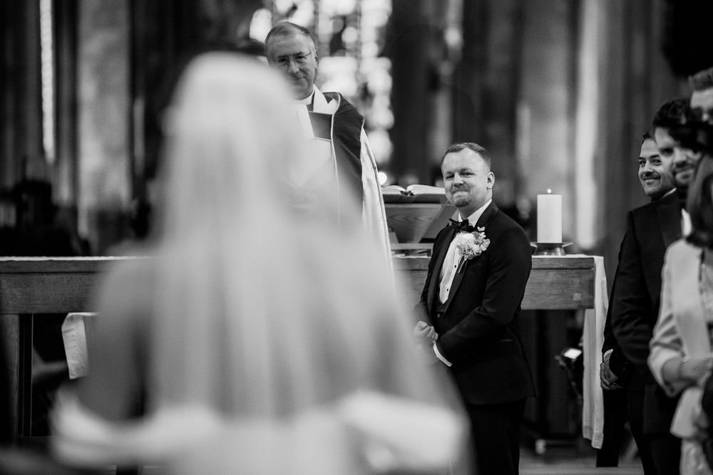 Black and white candid moment during wedding ceremony in traditional church setting.