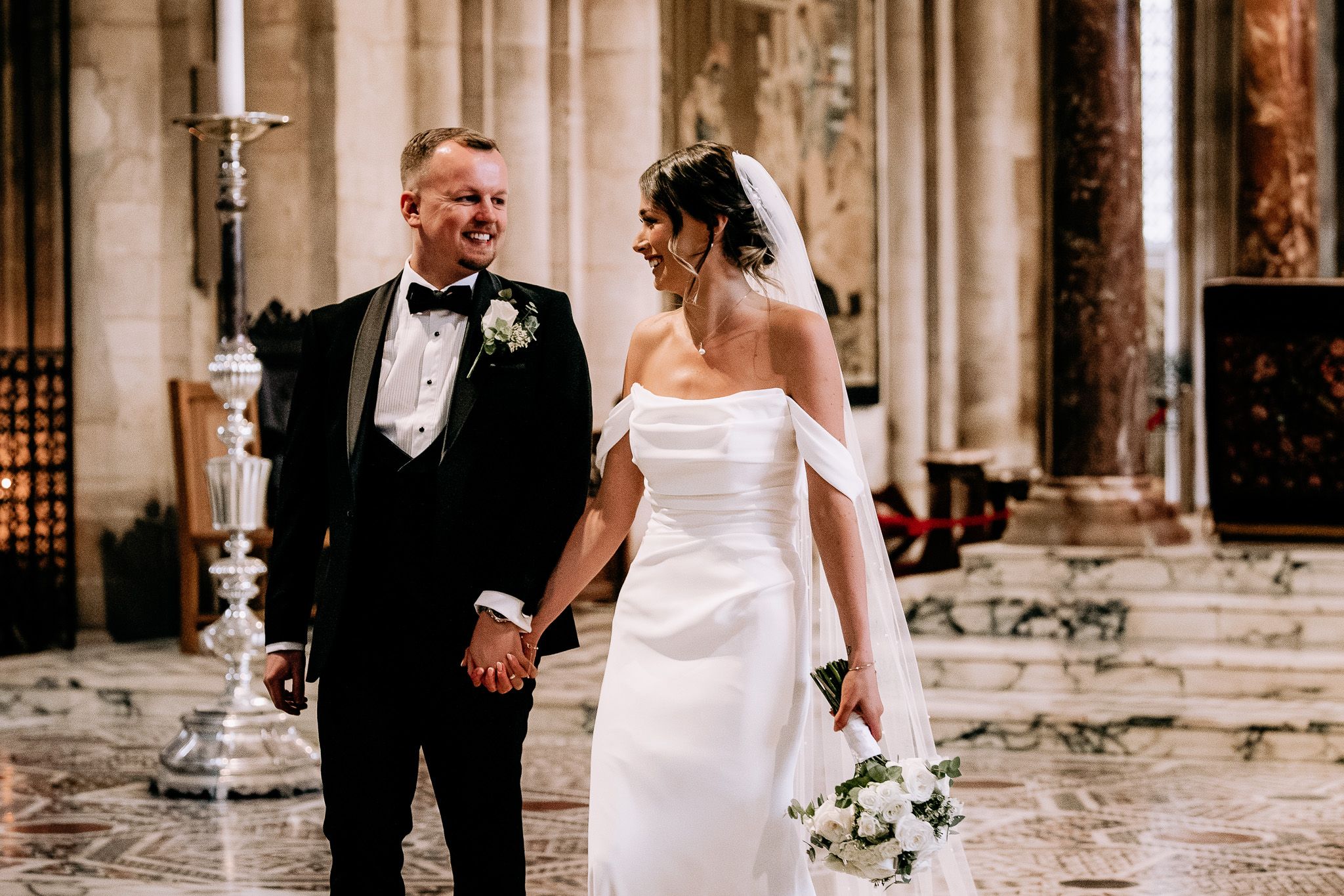 Elegant couple sharing a moment in formal attire inside a historic church setting.