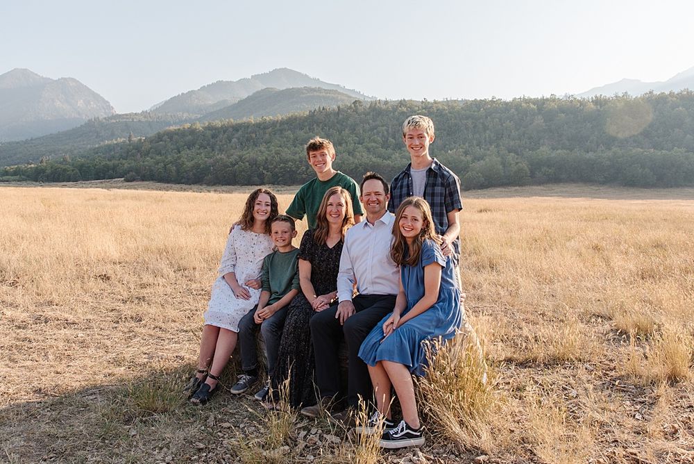 Group photo of people sitting together in mountain field at sunset.