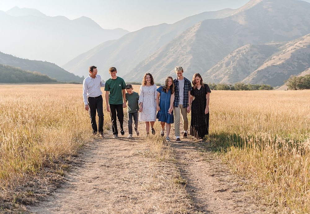 Group walking together on dirt path through golden mountain meadow.
