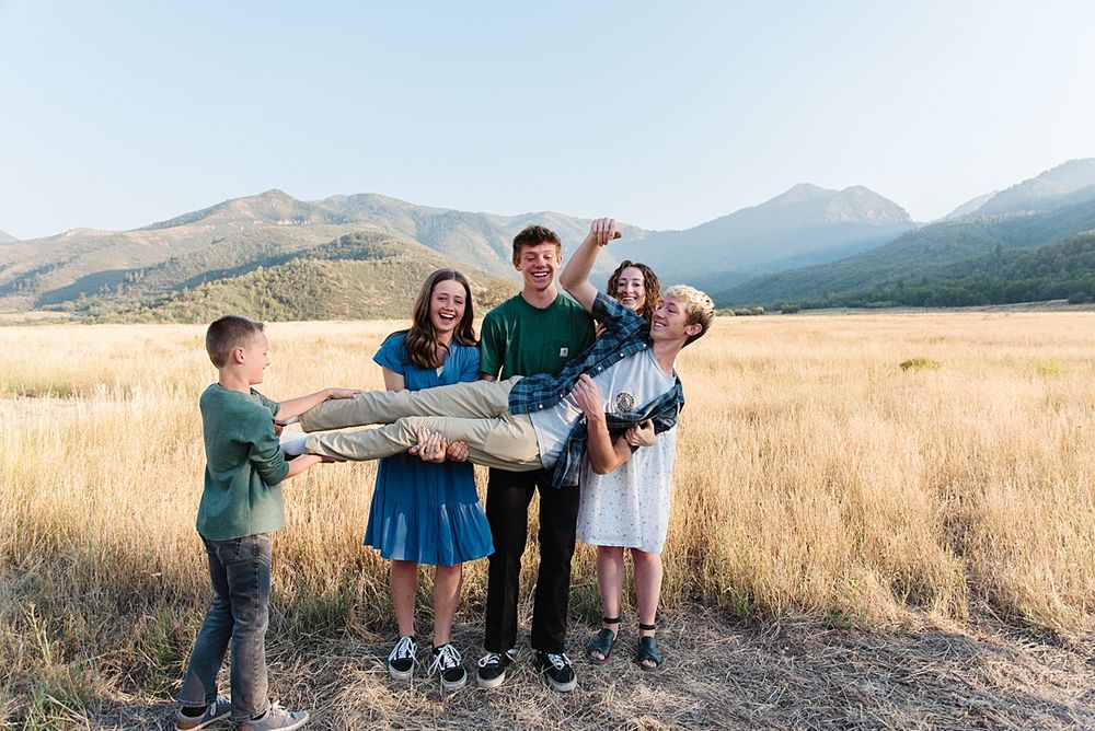 Family having fun together in a scenic mountain meadow at sunset.