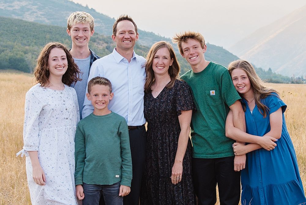 Family group portrait in mountain meadow wearing coordinated outfits.