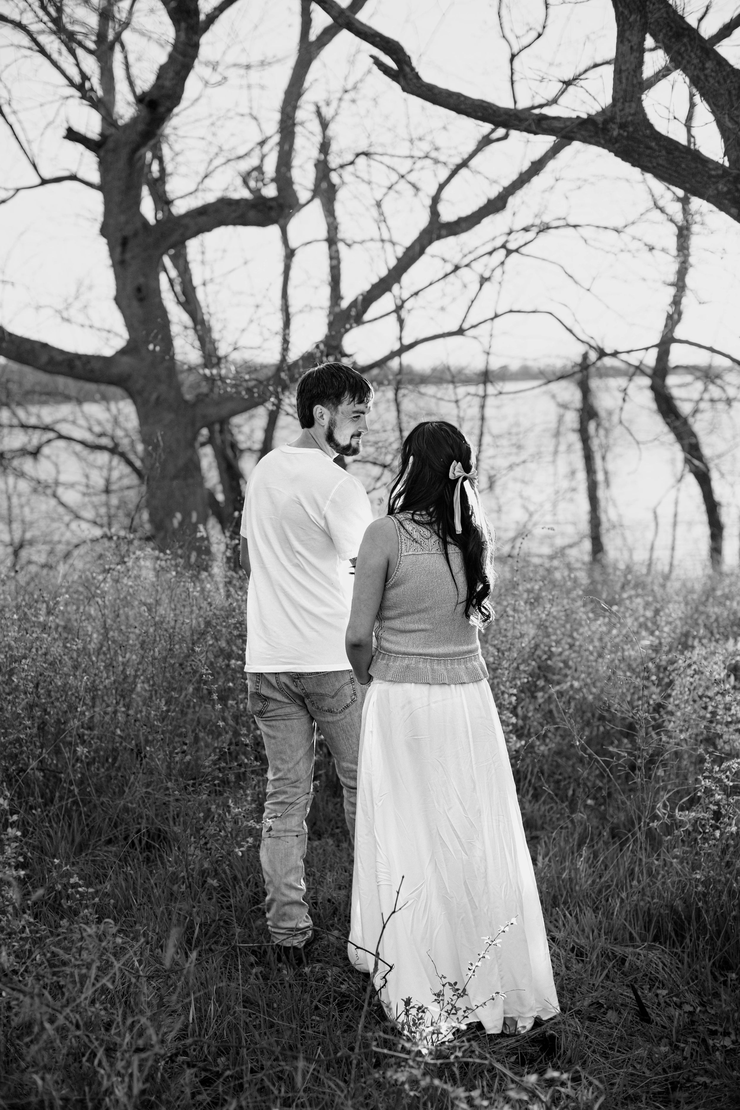 A man and woman walk away from the camera and look at each other during their Kansas City maternity photo session.