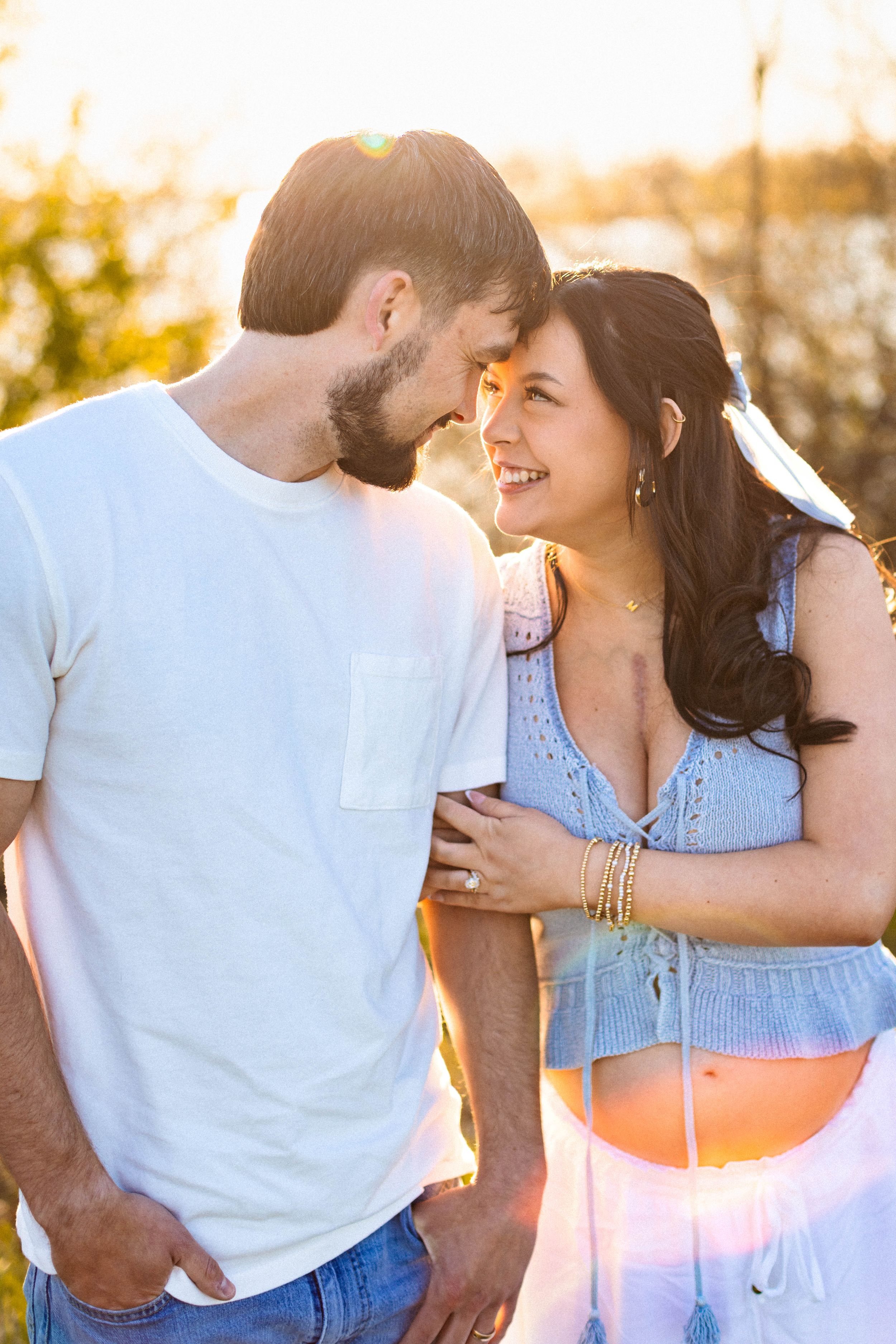 A pregnant woman and her husband lightly touch their foreheads together during their Kansas City maternity photo session.