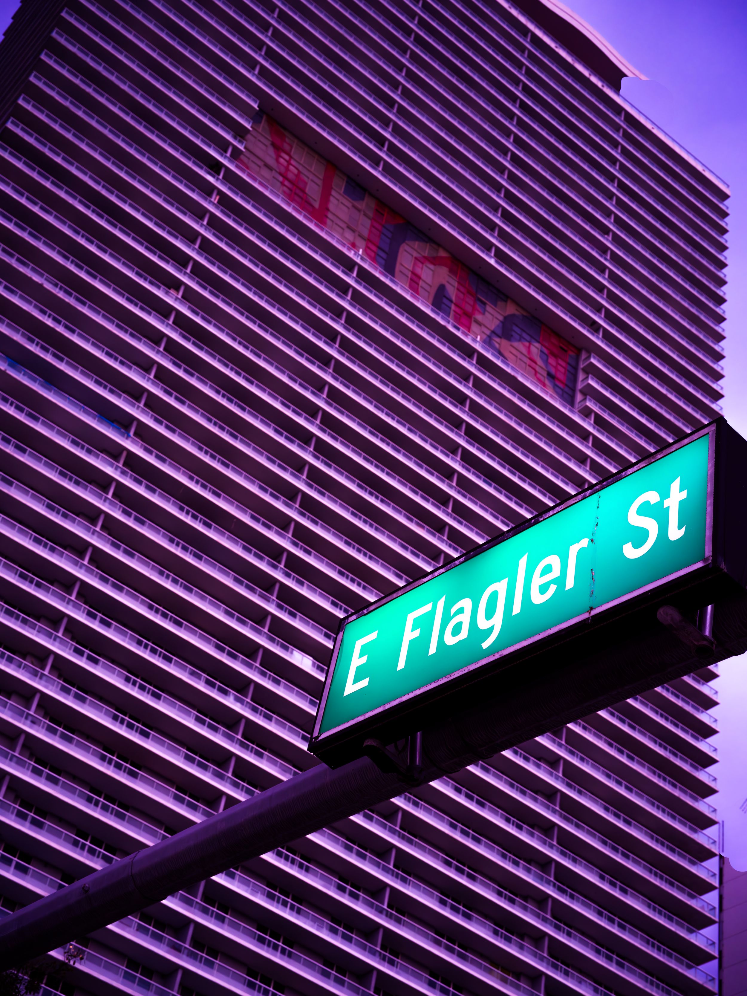 Urban photo of a high-rise building facade with a city street sign at dusk