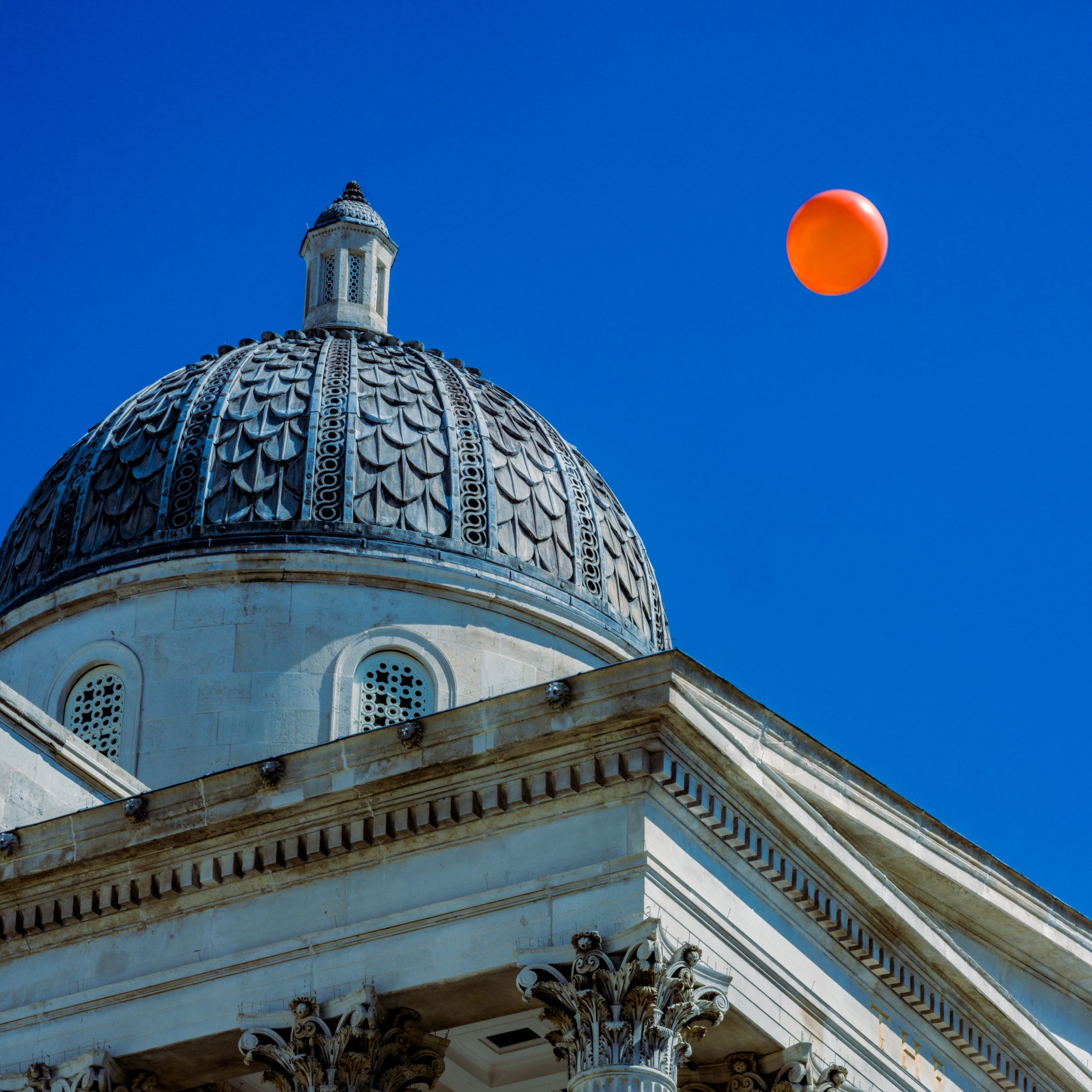 Architectural photo of a white domed building against a blue sky with the moon visible