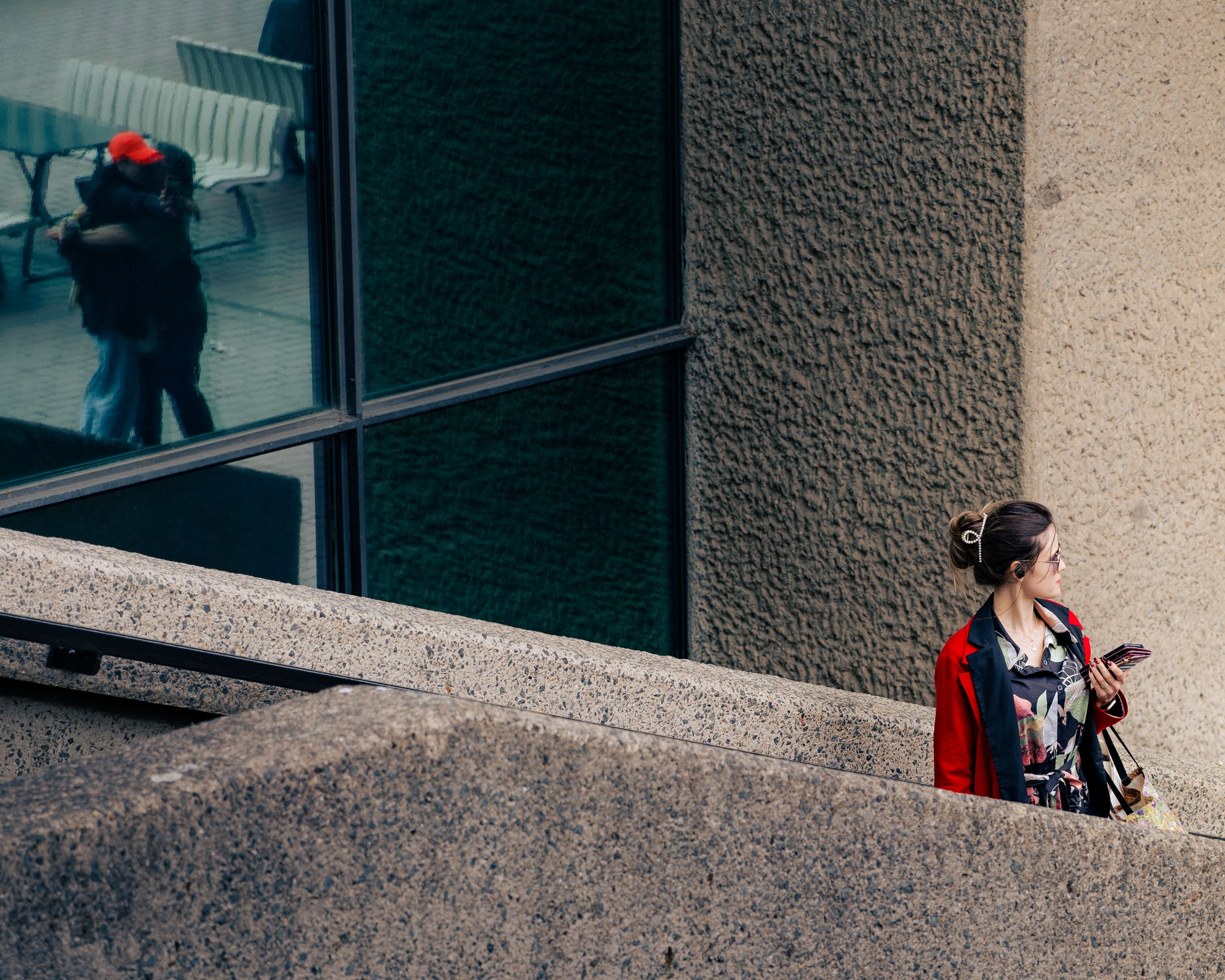 Street photography of a person walking near a glass building with reflections