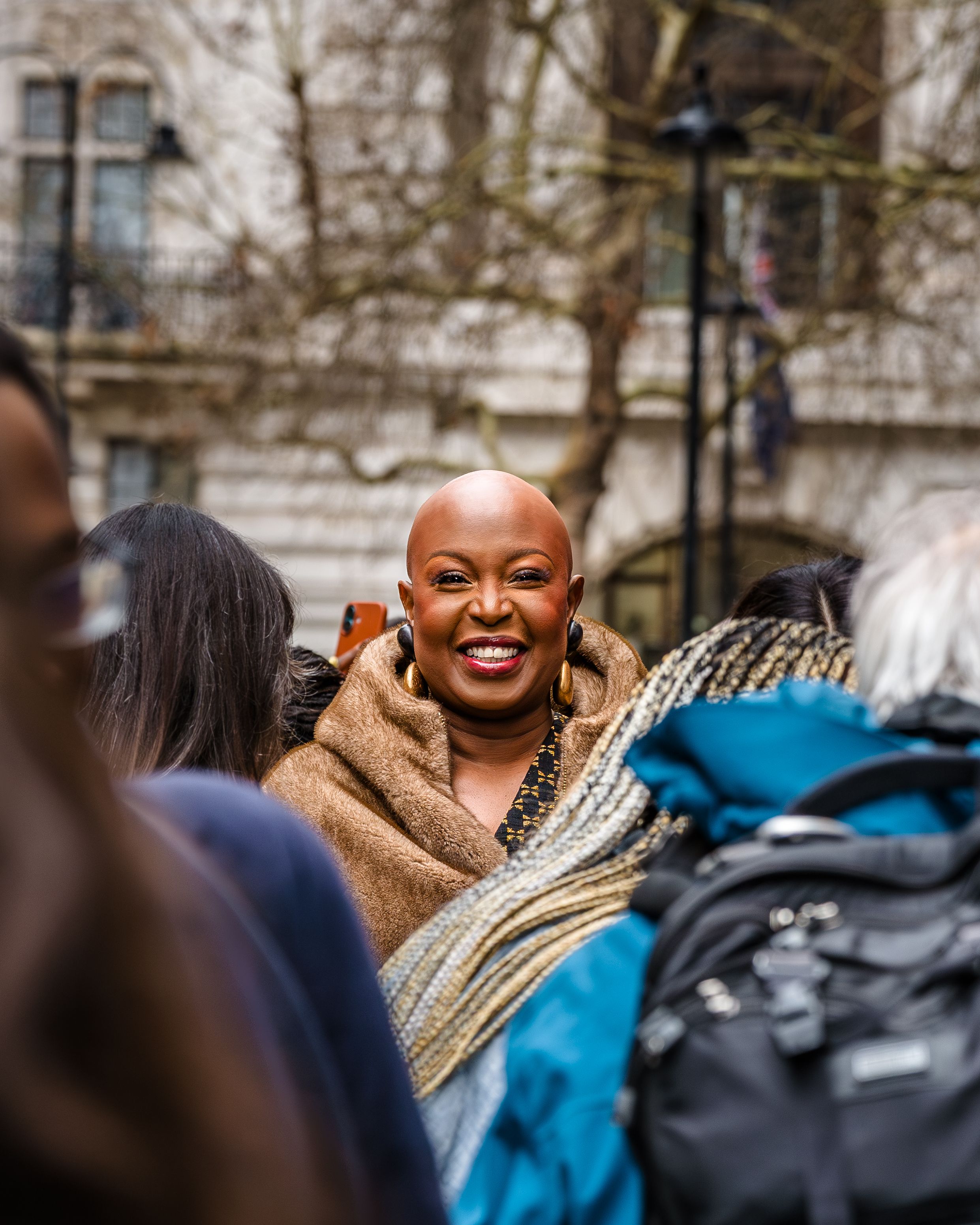 Candid street photography portrait of a smiling woman with curly hair in a crowd