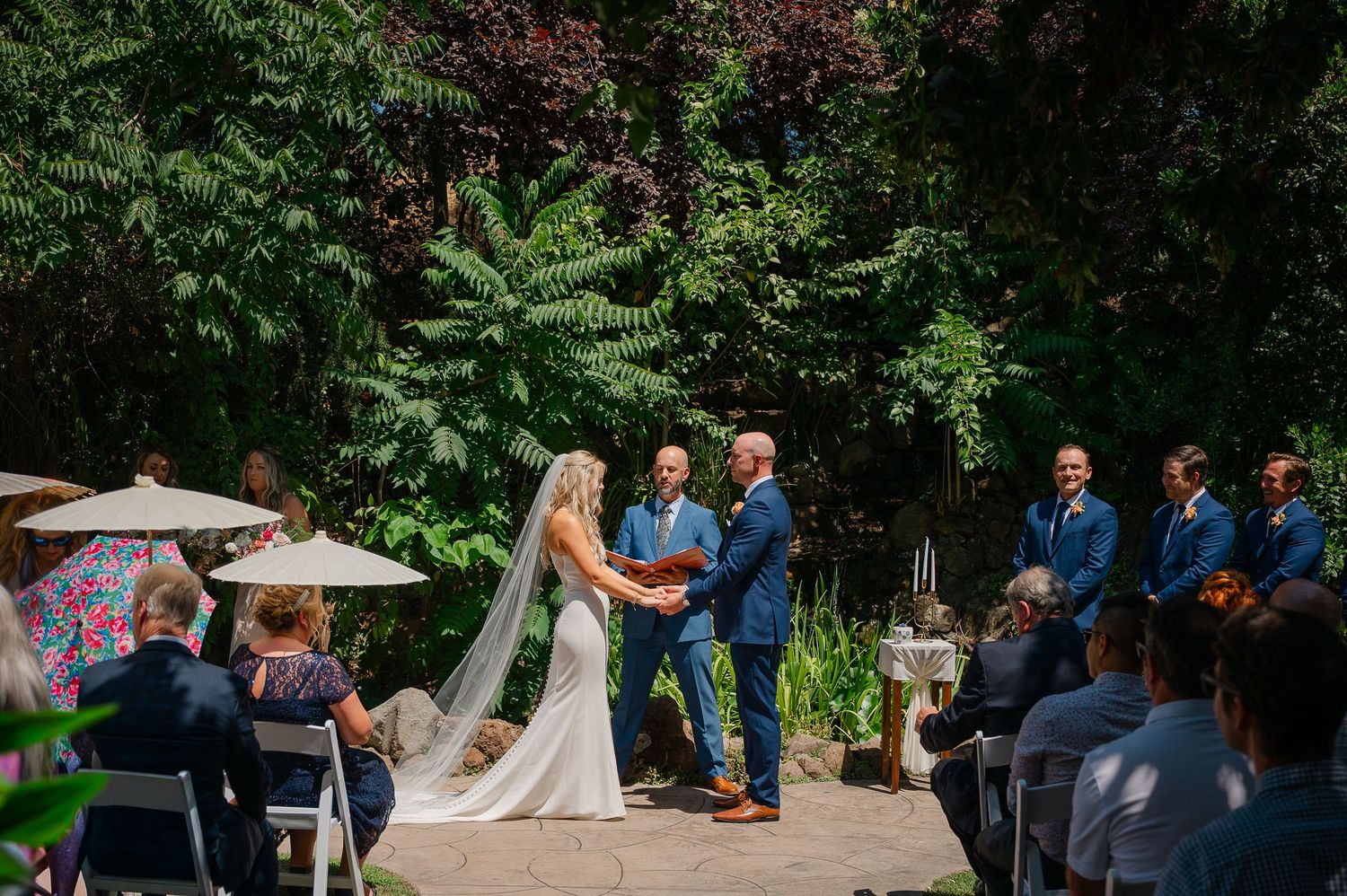 Outdoor wedding ceremony on a cliffside lawn overlooking the Pacific Ocean with guests seated in a semicircle.