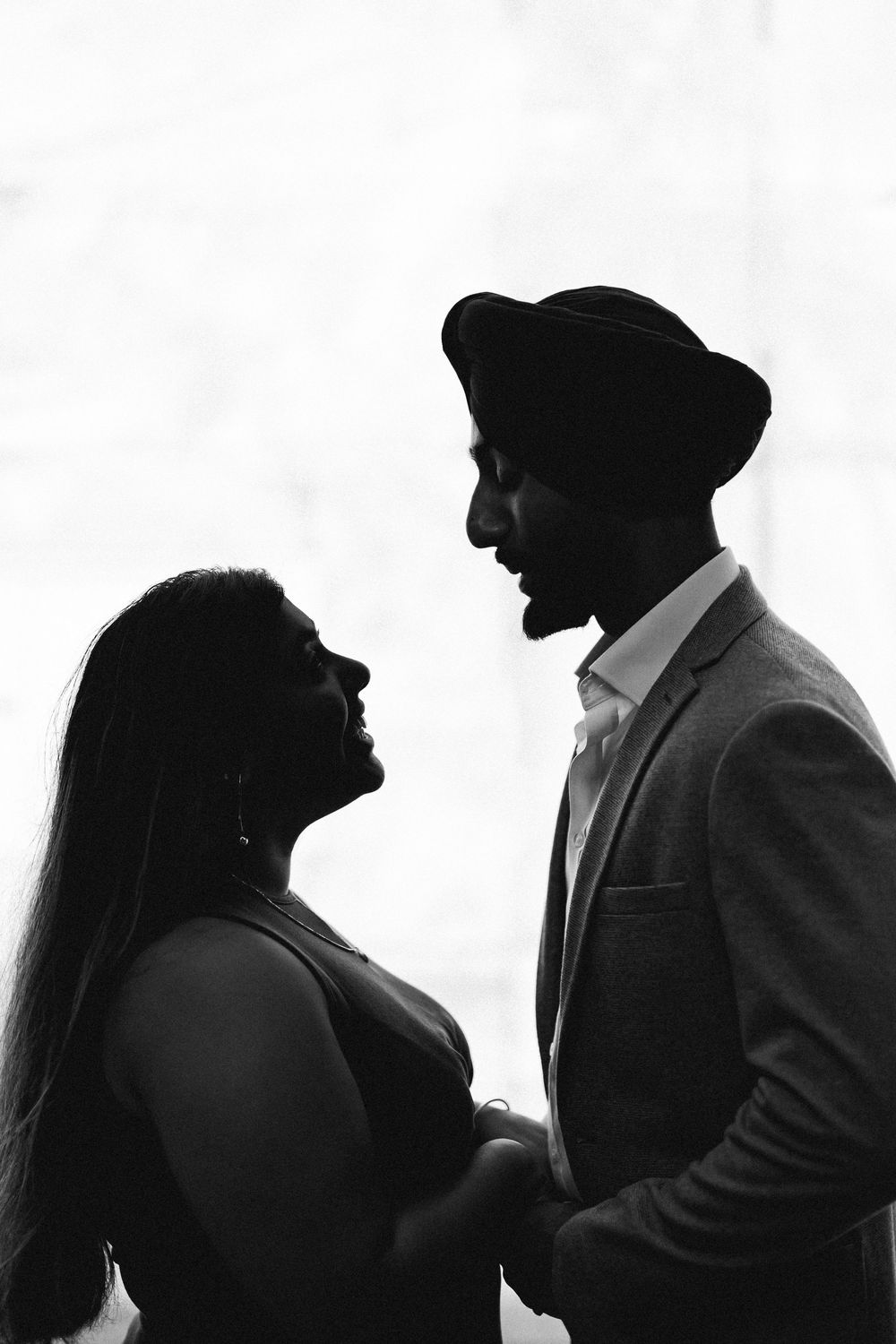 Black and white silhouette of a romantic couple gazing at each other, man wearing a turban and blazer.