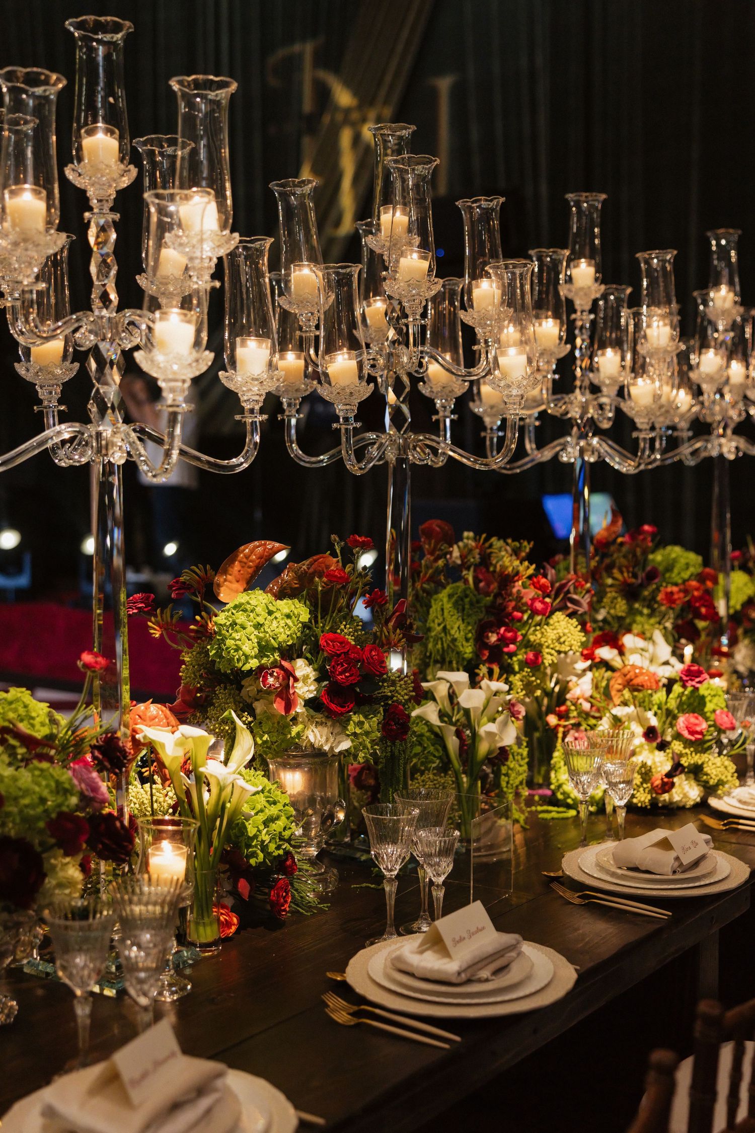 Luxurious wedding reception table with tall crystal candelabras, white candles, and colorful floral arrangements.