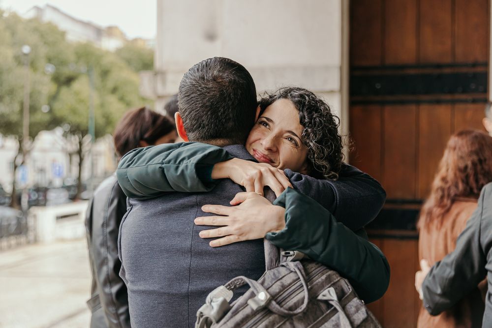 Two people sharing a warm hug outside near a wooden door.
