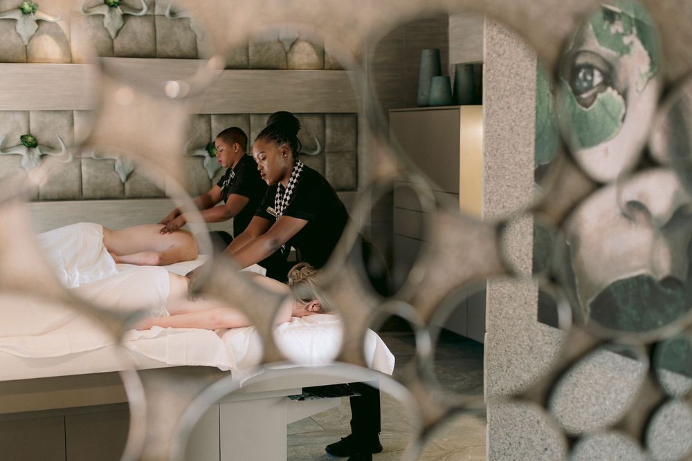 A spa therapist performs a relaxing massage treatment on a client in a serene, elegantly decorated spa room.