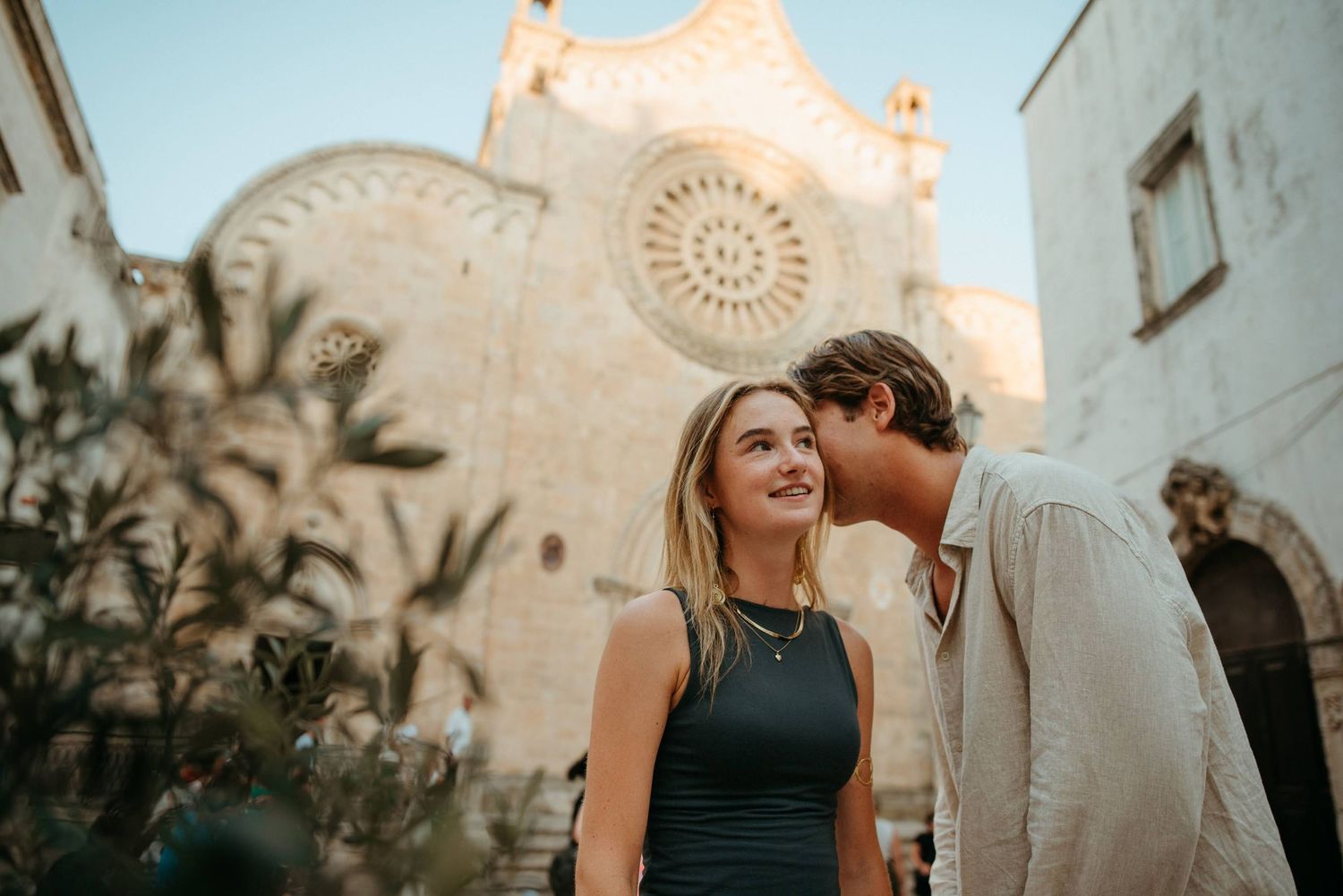 Couple sharing a romantic moment in front of a historic cathedral in Otranto, Italy.