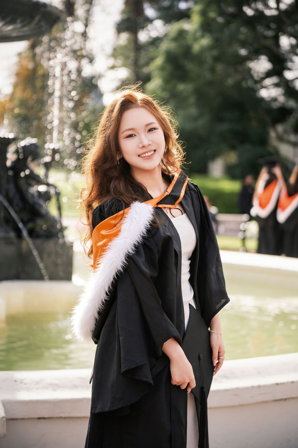Beautiful graduation portrait of a student smiling next to the Albert Park fountain near UoA.
