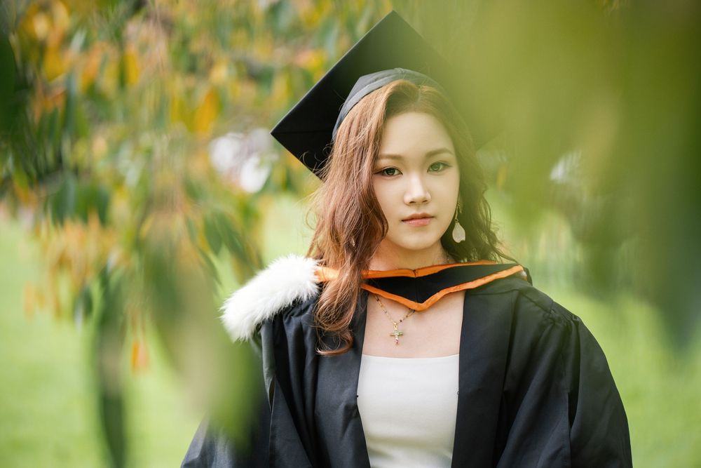 Artistic outdoor graduation photography of a student surrounded by autumn leaves at Albert Park.