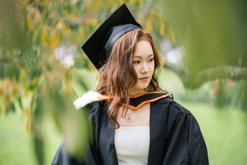Moody and natural graduation portrait framed by green leaves in Albert Park near the UoA campus.
