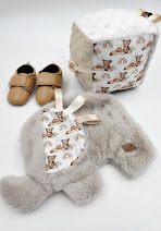 Baby gift set with bear-print fabric bag, soft gray plush toy, and tan leather baby shoes on white background.