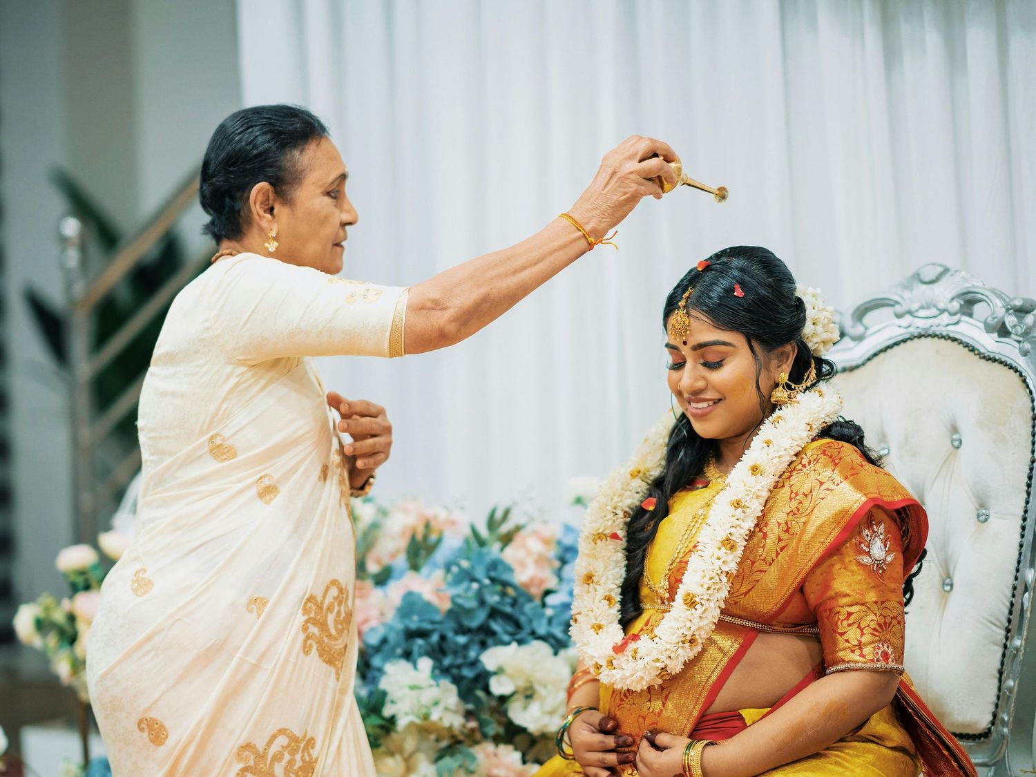 Indian couple in traditional pink attire seated at a decorated table during a baby shower celebration.