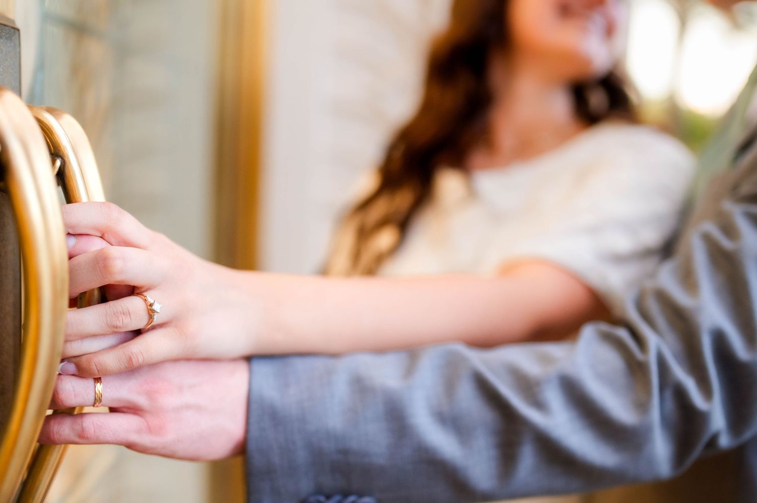 Close-up of bride and grooms hands touching a golden chair, showcasing wedding rings.