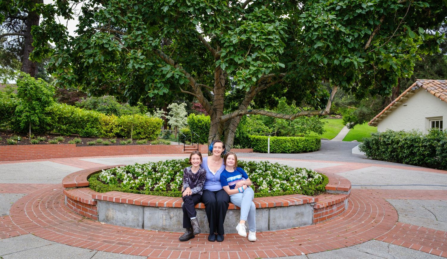 Happy family of five smiling outdoors in a lush forest setting, parents with three children posing together.