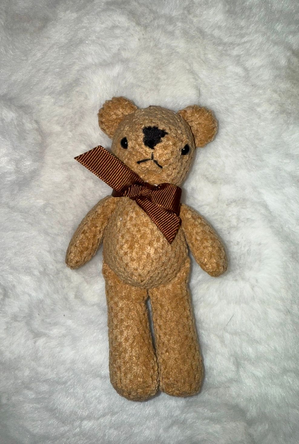 A tan knitted teddy bear with brown bow tie photographed from multiple angles on white background.