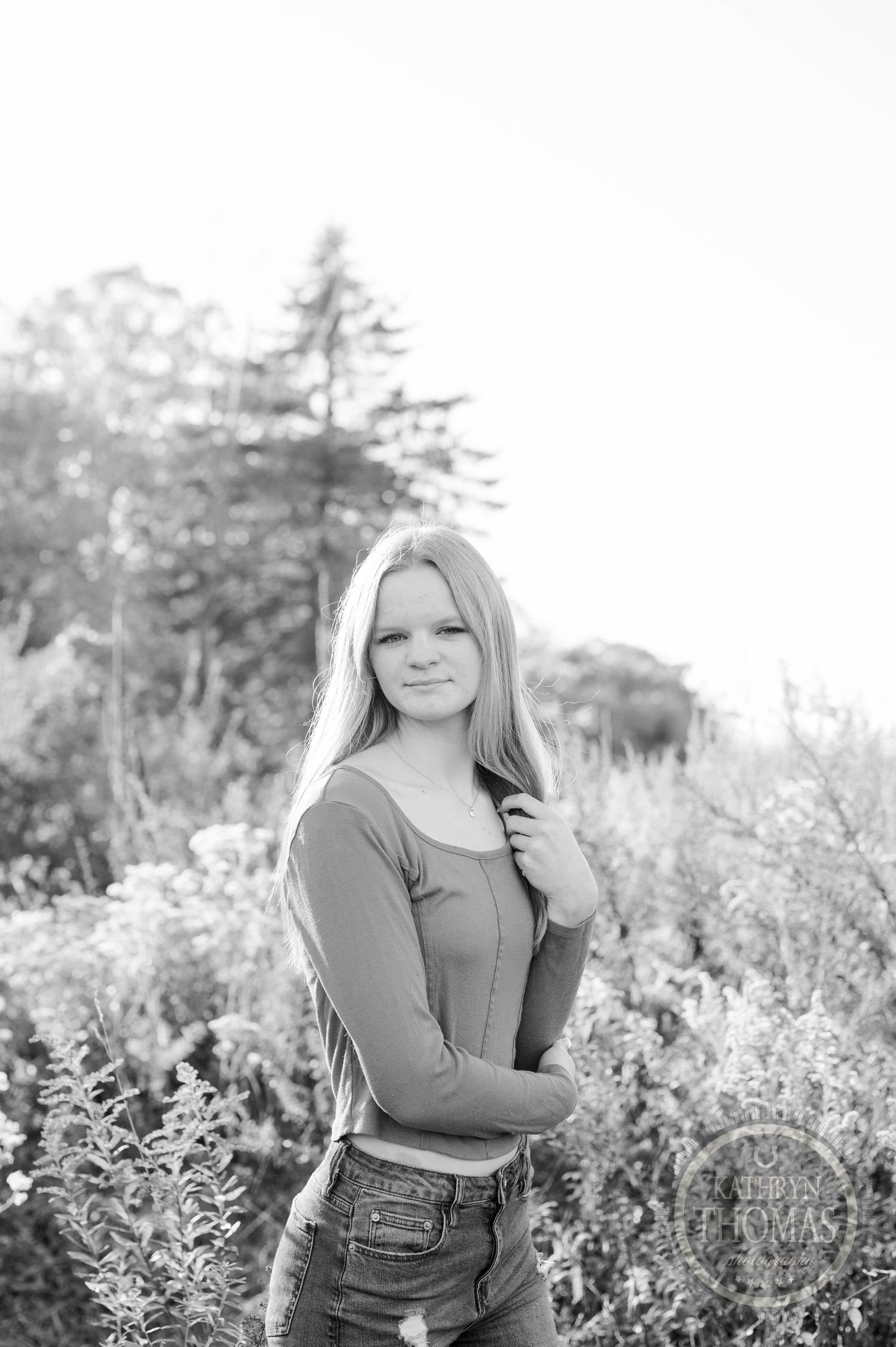 Black and white portrait showcasing casual style in an outdoor natural setting.