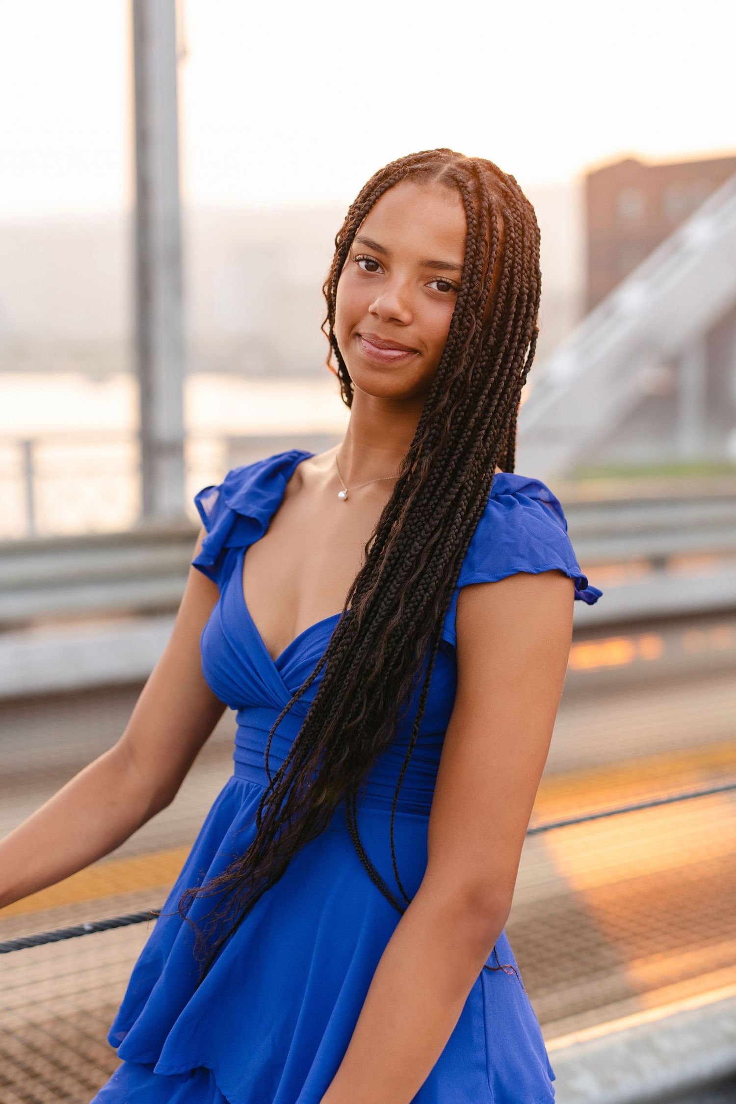 Standing in casual summer attire on an empty road beneath a white steel bridge structure with architectural details.