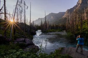 The trail to St. Mary's Falls in Glacier National Park at sunrise with photographer taking a picture