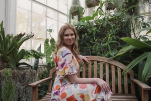 Portrait of a woman sitting sideways on a bench.