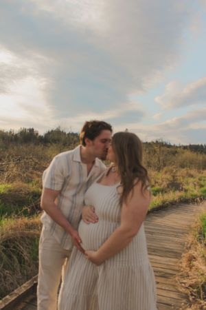 Portrait of a pregnant couple kissing and holding the baby bump.