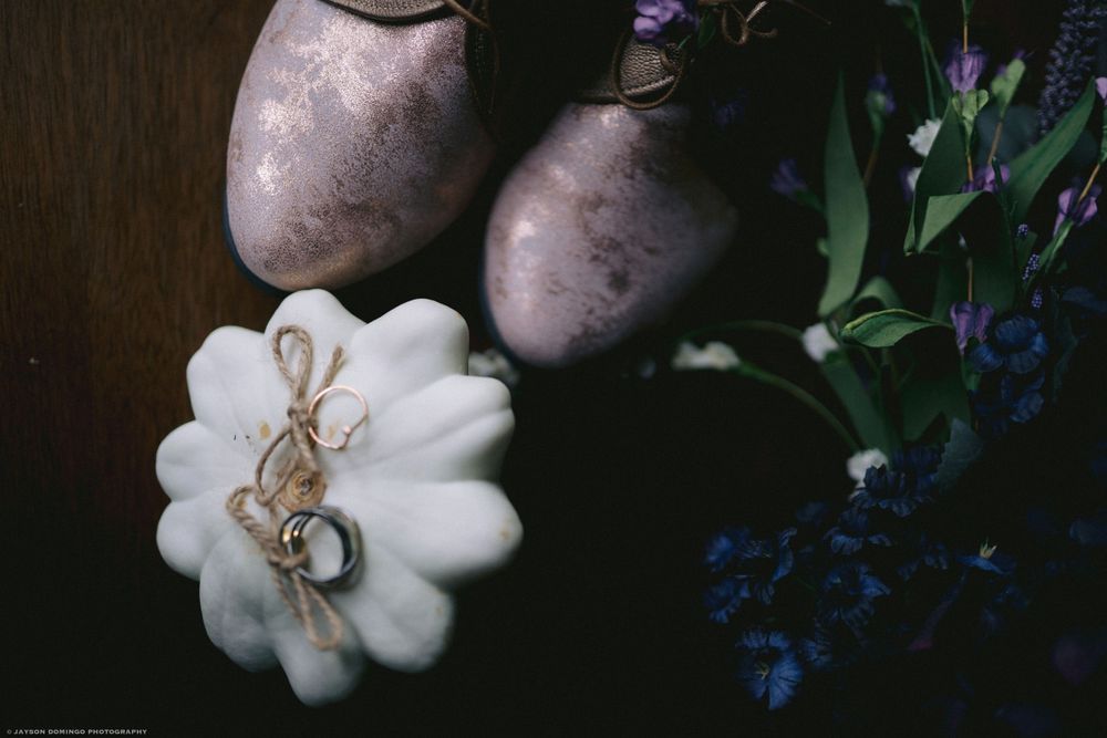 White decorative pumpkin with twine accent displayed alongside purple flowers and potatoes.