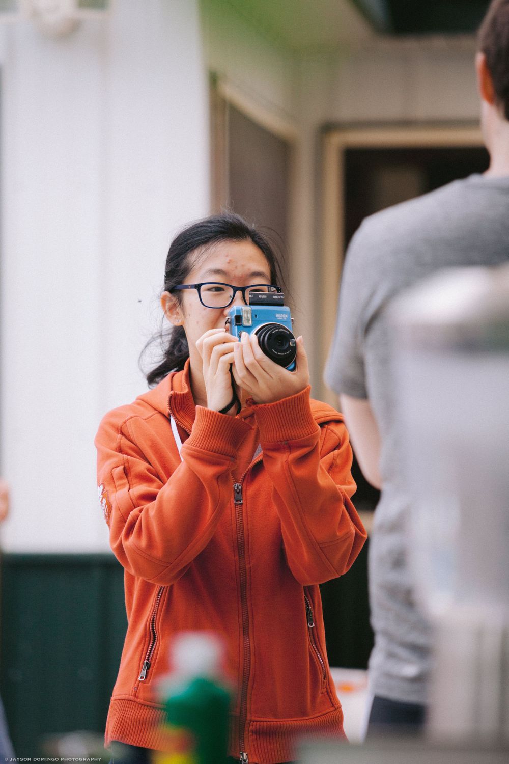 Photographer in an orange fleece jacket capturing photos with a professional camera.
