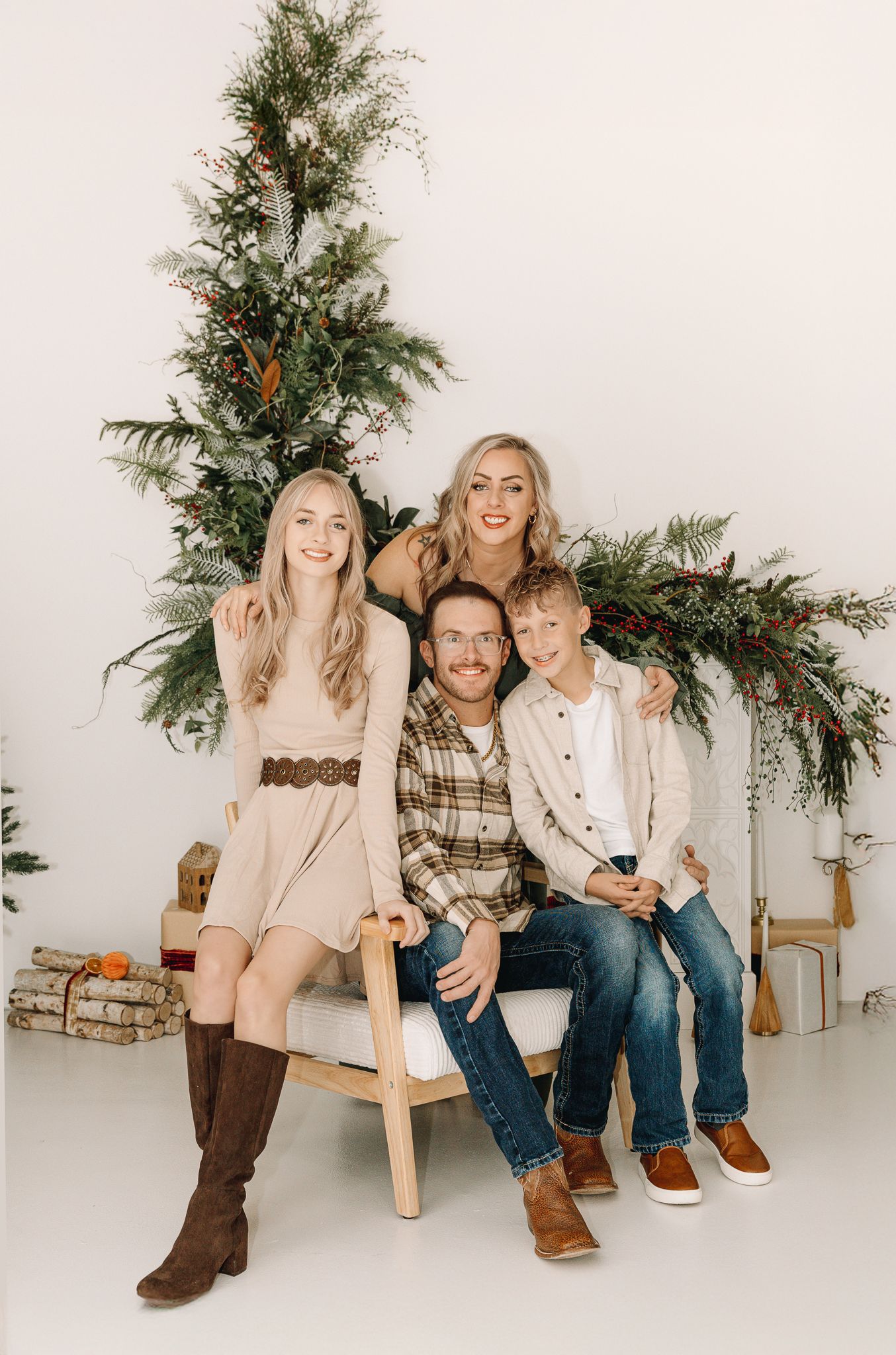 Indoor Christmas family photo of four in a Greeley, Colorado studio with parents and two kids smiling together.