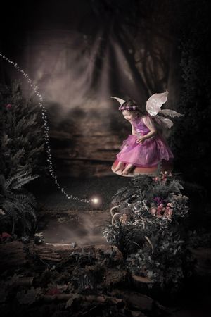 A fairy in purple and pink floats magically above an enchanted forest floor with sparkling lights.