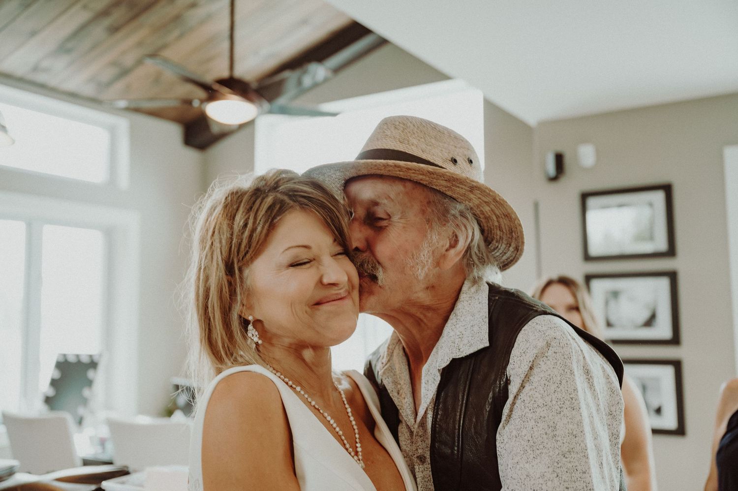 A tender moment shared during a rustic indoor celebration with wooden beams and ceiling fan.