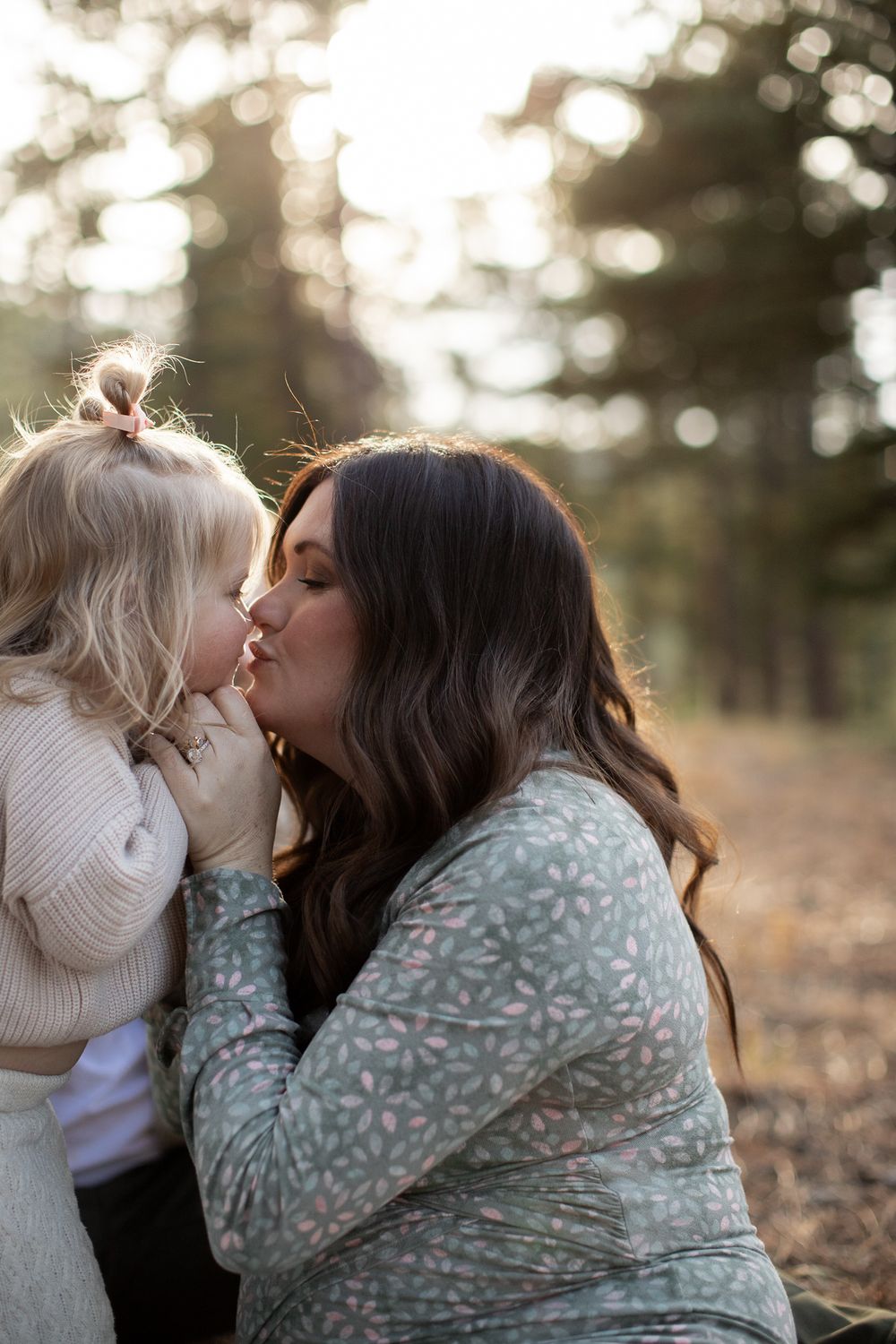 A tender moment between mother and child with soft bokeh lights in the background during golden hour.