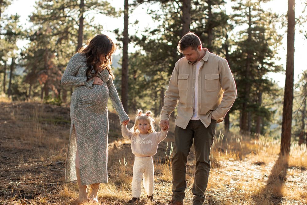 A family walks together in a sunlit forest during golden hour on a fall afternoon.