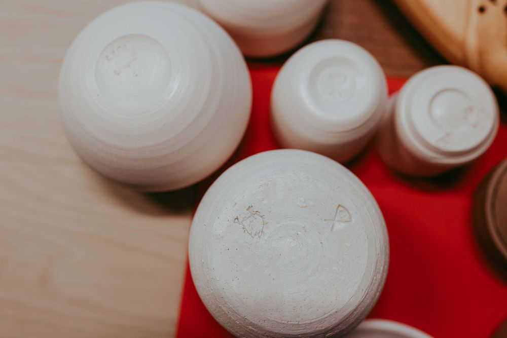 White ceramic bowls and containers arranged on a red surface with a wooden background. Whitney Popp. Arizona photographer