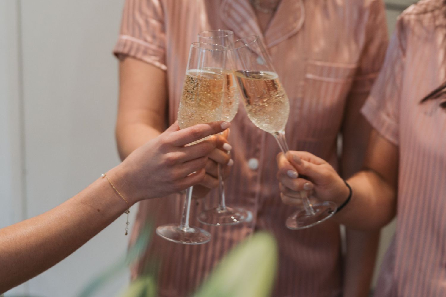 People hold delicate champagne flutes filled with sparkling wine as they toast in celebration.