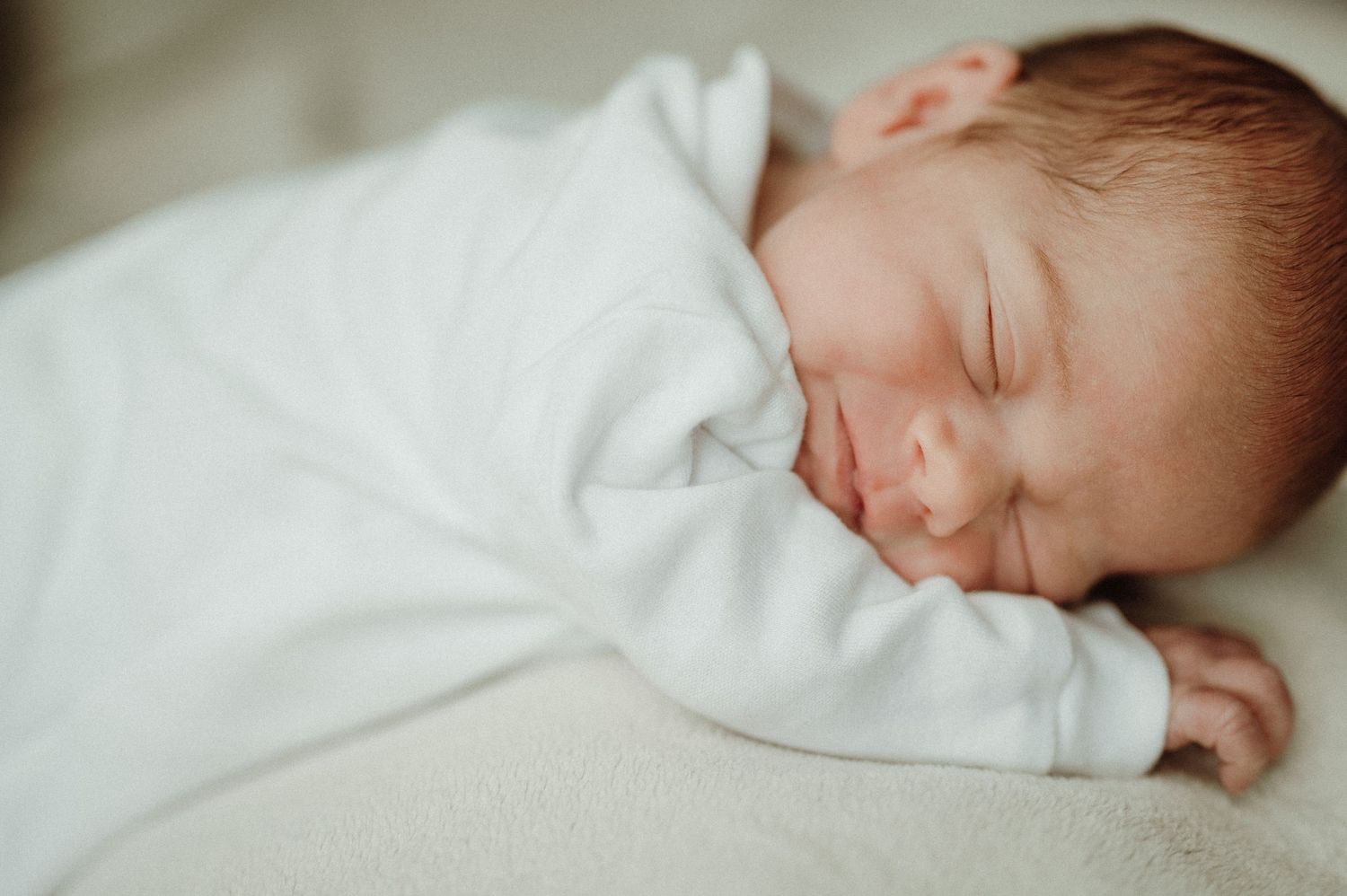 Peaceful sleeping baby wrapped in soft white blanket.